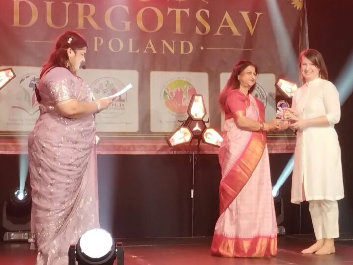 A laureate receives her glass trophy on stage at Durgotsav Poland
